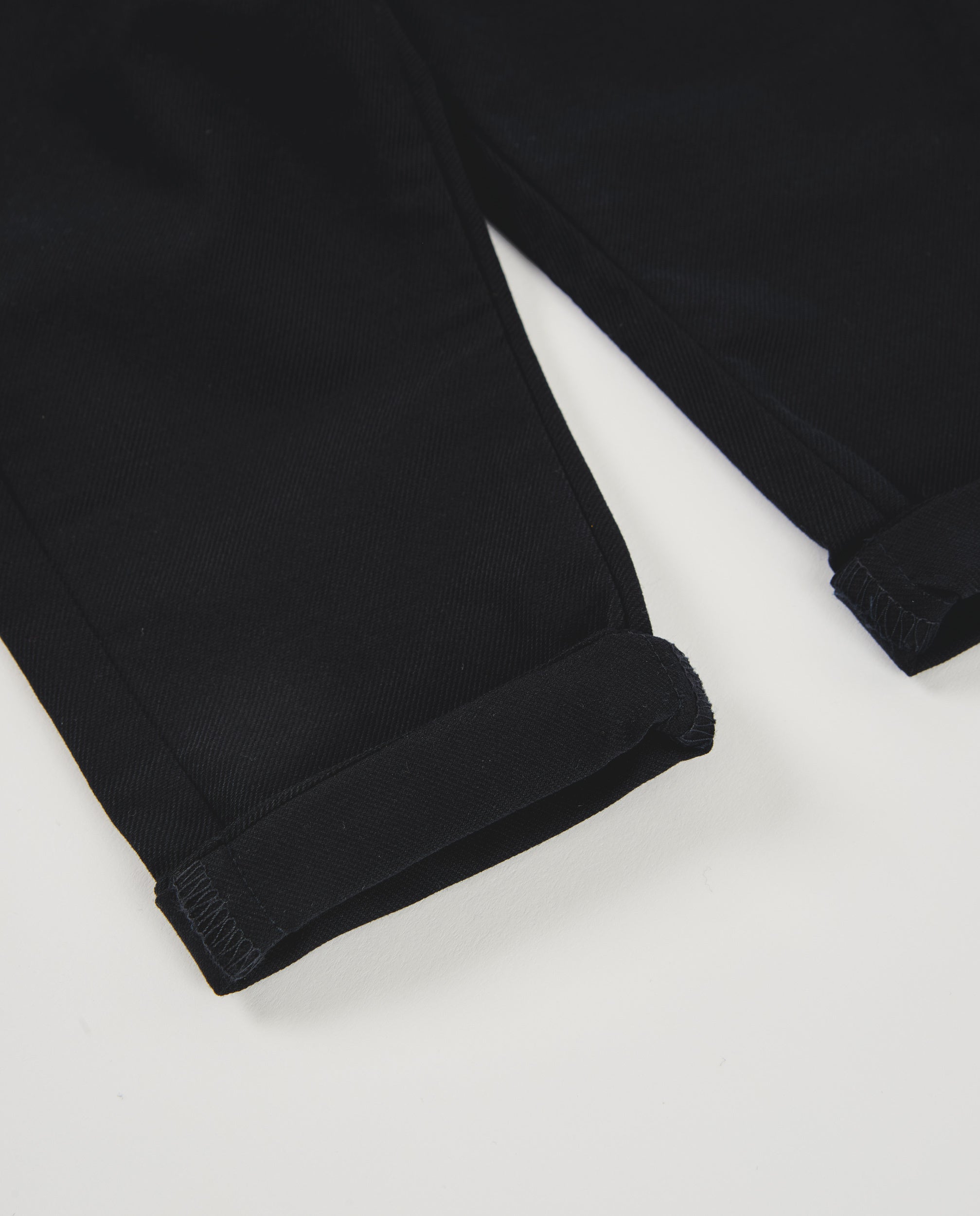 Pantalón de niño color negro con bolsillos y vuelta en el bajo
