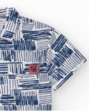 Chemise blanche pour garçon avec imprimé géométrique bleu et poche décorative.