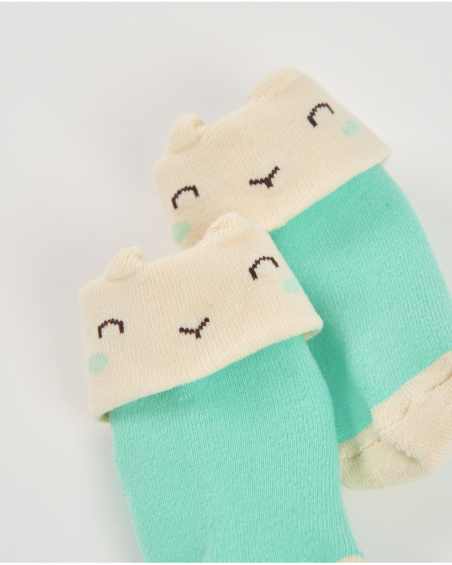 Chaussettes pour nouveau-né en vert et crème avec motif visage souriant.