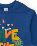 Maglietta a maniche lunghe per bambino color crema con stampa di alberi e frase decorativa.